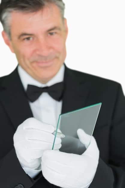 Close-up of a person in professional attire delivering a pitch at a biotech event, holding a tablet displaying key data points. The background shows blurred figures of other attendees and event signage.