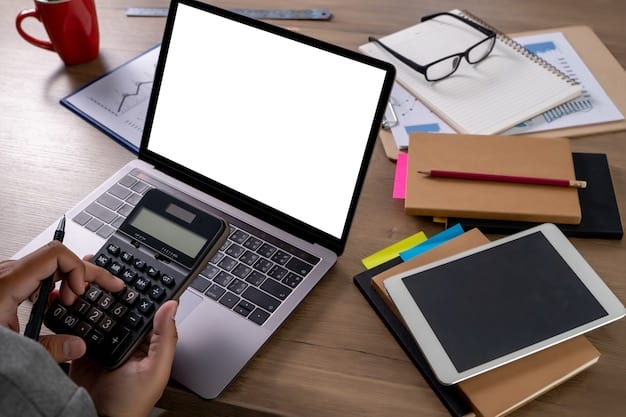 A person holding a calculator and looking at a spreadsheet on a computer screen, with various tax forms scattered on the desk.